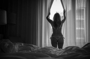 Sabahın erken saatlerinde bir kadın pencerenin önünde duruyor.