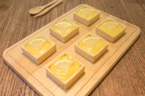 Свежий вкусный десерт из лимонного пирога, красиво подаваемый на деревянном кубике — стоковое фото
