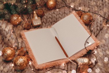 Gri örülü arka planda Noel süslemeleri ve düz uzanma içeren şampanya dolu bir defter aç.