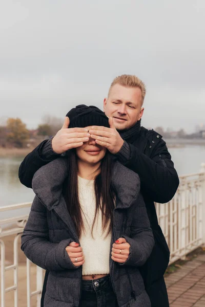 Ερωτευμένος με το ζευγάρι, ο άντρας καλύπτει τα χαμογελαστά μάτια των κοριτσιών με τα χέρια του — Φωτογραφία Αρχείου