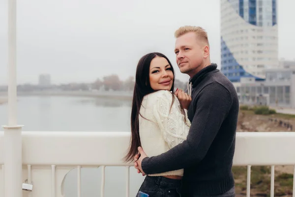Una joven pareja en suéteres se acurruca en el puente —  Fotos de Stock