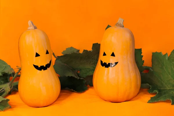 Две тыквы с веселыми лицами на Хэллоуин на оранжевом фоне, копирайт — стоковое фото