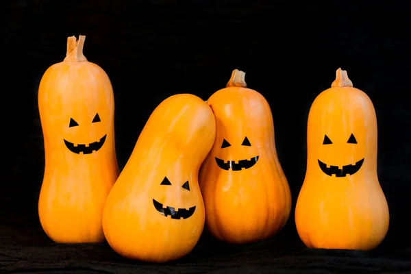 Четыре тыквы с веселыми коварными лицами на Хэллоуин на черном фоне — стоковое фото