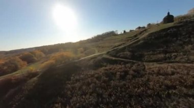 FPV hava aracı görüntüsü. Dnipro nehri yakınlarındaki sonbahar orman tepelerinin üzerinde uçuyorlar.