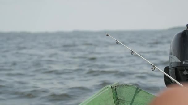 Un pescatore cattura il pesce seduto su una barca di legno. — Video Stock