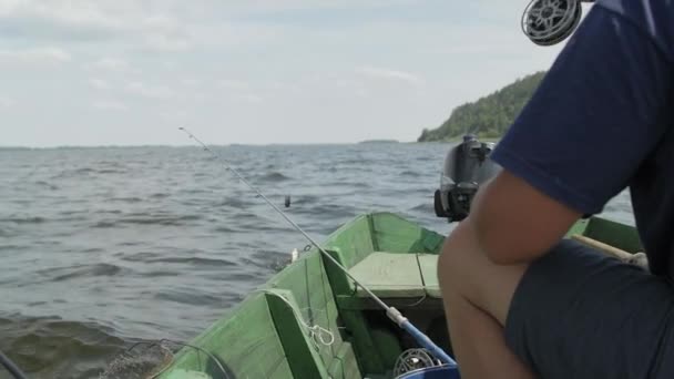 Un pescatore cattura il pesce seduto su una barca di legno. Il momento in cui il pesce catturato. — Video Stock