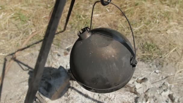 Heating water in a kettle on a fire during a hike — Stockvideo