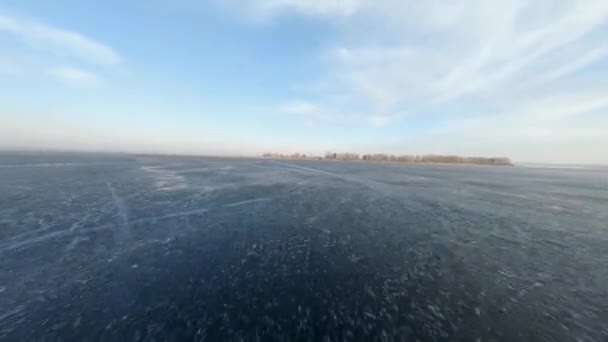 Widok drona FPV na niski i szybki lot nad zamarzniętą rzeką o zachodzie słońca — Wideo stockowe