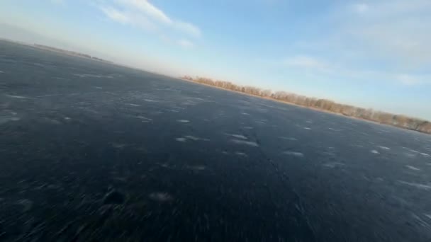 FPV vista del avión no tripulado de vuelo bajo y rápido sobre el río congelado al atardecer — Vídeo de stock