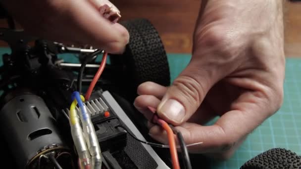 クローズアップ無線制御モデルバギー車。モデルのバッテリーを接続するマスターの手 — ストック動画