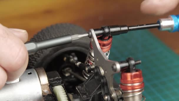 Close-up radio control model buggy car. The hands of the master disassemble the shock absorber — Stock Video