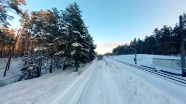 FPV dron görüntüsü. Gün batımında kış ormanında tren yolu üzerinde hızlı uçuş.