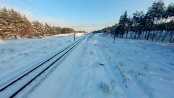 Widok drona FPV. Szybki lot nad koleją w zimowym lesie o zachodzie słońca — Wideo stockowe