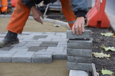 Bir işçi beton döşeme levhalarını alır, onları kuma serer ve bir otopark inşa eder..