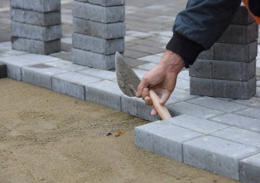 İnşaatçılar yol kiremitlerini kumun üzerine sermişler..