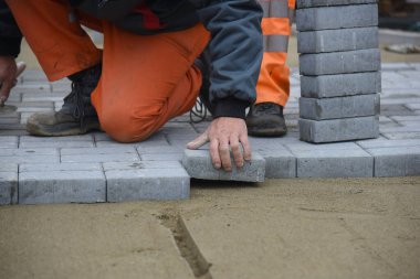 Bir işçi kumsala gri beton döşemiş. Arabalar için yol yapımı..