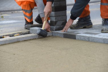 İşçiler gri beton döşeme döşeyip yeni bir yaya yolu inşa ediyorlar..