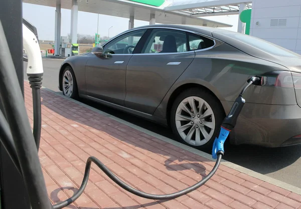 The electric car is connected to a charging station.Charging the car with electricity,a power source for batteries.