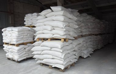 Torbalar un ve tahıl paletlerin üzerine istiflenmiş, fabrika deposunda depolanmış. Yükleme ve daha fazla ulaşım için hazırlanmış malzeme.