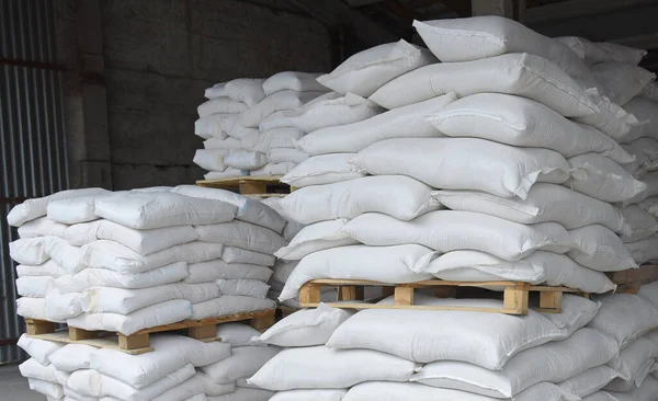 Bags of flour and grain in the warehouse are stacked on pallets, the factory is processing and sorting.