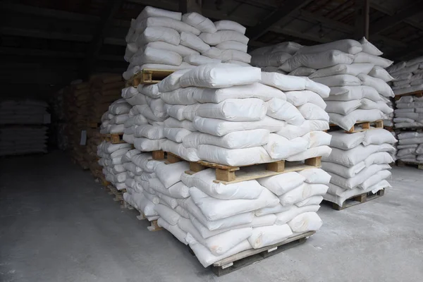 Bags of flour in the warehouse of the processing plant are stacked on pallets, a warehouse of finished grain products.