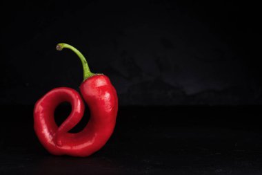 Bir kırmızı biber siyah arka planda salyangoza benzer. Kopyalama alanı, yakın plan..