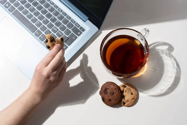 Tangan Wanita Memegang Biskuit Cokelat Samping Laptop Secangkir Teh Dua — Stok Foto