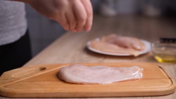 Kvinnors händer krydda kycklingbröst med salt och peppe. — Stockvideo