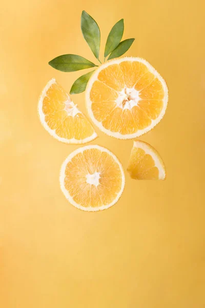 Irisan Oranye Segar Dengan Daun Hijau Pada Latar Belakang Kuning — Stok Foto