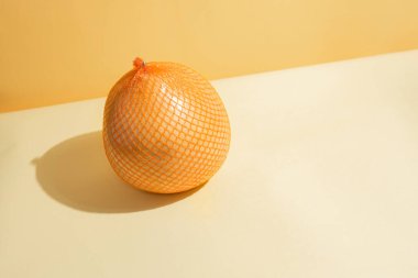 Sarı ve turuncu arkaplanda sarı ve turuncu bir arkaplandaki ağ ambalajı içinde sarı taze nargile, yaklaş. Modern izometrik konsept.