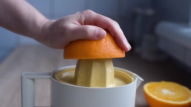La mano femenina exprime el jugo de las naranjas orgánicas en un exprimidor — Vídeos de Stock