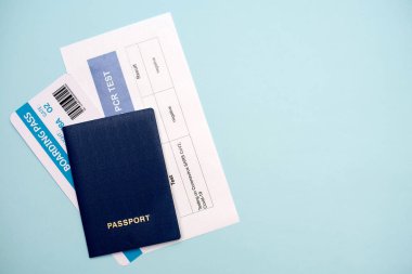 Documents for air travel during the COVID-19 epidemic: passport, ticket, COVID-19 PCR test on a blue background, close up.