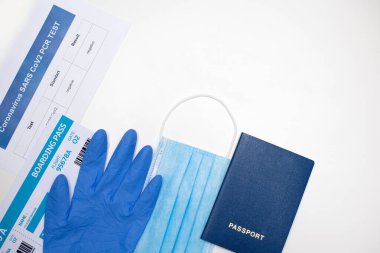 Documents and items for air travel during the COVID-19 epidemic: passport, ticket, PCR test for COVID-19, face mask, gloves on a white background, copy space.