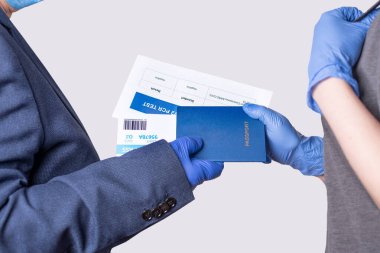 The officer takng documents from the passenger to check. Passport, ticket, covid-19 PCR test, close up.