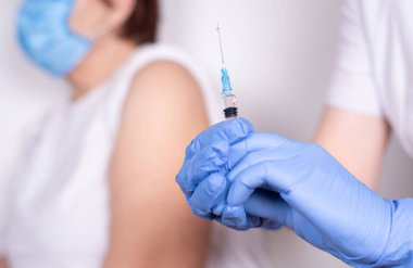 Hands in gloves preparing a syringe to vaccinate an old woman against covid-19, close up. Coronavirus vaccination concept.