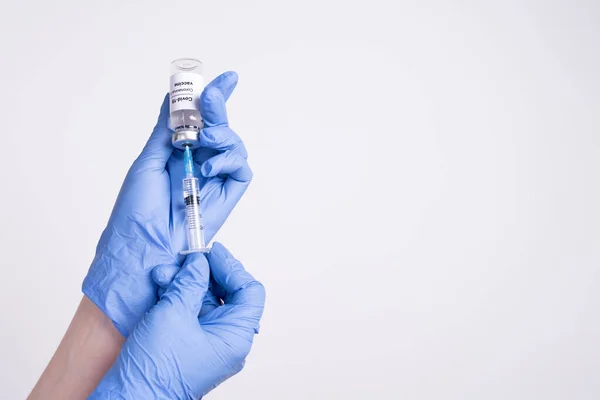 Hands in blue medical gloves drawing a syringe with covid-19 vaccine from a vial, copy space, close up. Coronavirus vaccination concept.