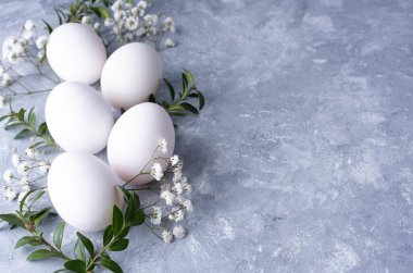 Yeşil dallı beyaz yumurtalar ve gri arka planda çingene, üst manzara, düz yatış, yakın çekim. Paskalya arkaplanı.