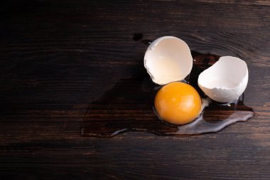 Kırık tavuk yumurtası, yumurta sarısı ve yumurta beyazı. Koyu ahşap arka planda kabukları var. Köy usulü.