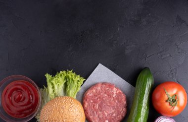 Siyah zemin üzerinde sığır burger, çiğ biftek köftesi, soğan, marul, domates, salatalık, ketçap, kapak, kopyalama alanı..