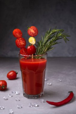 Bir bardak Bloody Mary, domatesler, arka planda biberiye ve acı biber, domates suyuyla alkollü kokteyl, yakın çekim..