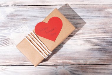 Babalar günü hediyesi kağıt üzerinde kalp şeklinde tebrik kartı beyaz ahşap arka planda, çevre dostu ambalaj konsepti, üst manzara, kapat..