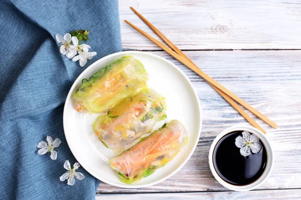 Beyaz bir tabakta yumurta ruloları ve beyaz ahşap arka planda soya sosu, Asya mutfağı, yakın çekim..