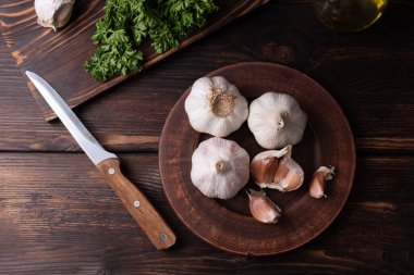 Koyu ahşap bir arka planda, sarımsak ve karanfil başları ile tabak, kırsal tarzda, yakın çekim.