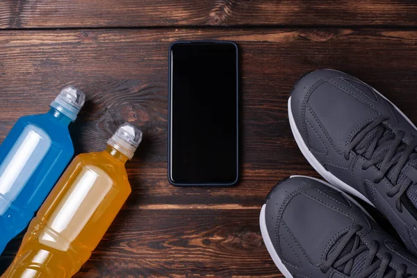 Sepatu Abu Abu Smartphone Dan Dua Botol Minuman Isotonik Kayu — Stok Foto
