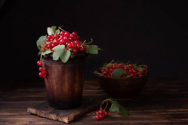 Kil bir kasede olgun kırmızı frenk üzümü, koyu bir arka planda, yaz meyveleri, yakın çekim.