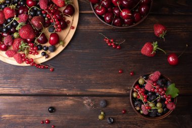 Sağlıklı böğürtlenler, ahududular, çilekler, tatlı kirazlar, koyu ahşap arka planda üzümler..