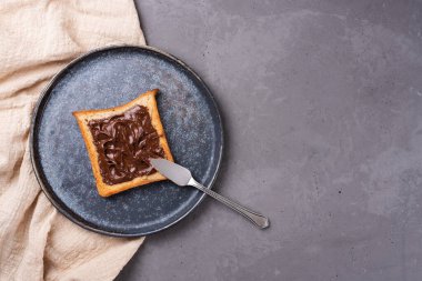 Gri beton kaplamalı bir tabakta çikolata ezmeli tost, tekstil, kopyalama alanı.