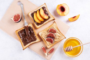 Fıstık ezmesi, çikolata üzerine meyveli tost beyaz arka planda kesme tahtası, sağlıklı tatlı kahvaltı, yakın plan..