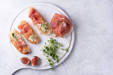Jambon, ricotta ve mikro yeşillik antipasto, beyaz arka planda jambonlu crostini, yakın plan..