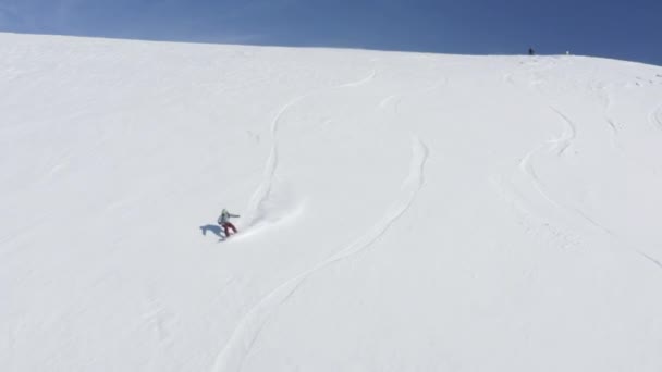 Snowboarder sur snowboard sur pente enneigée en hiver vue aérienne montagne — Video